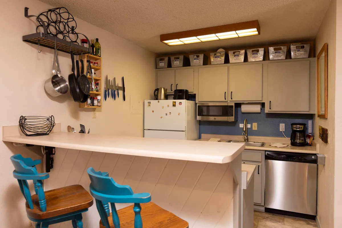 This image features a welcoming kitchen space with a broad kitchen counter, bar stools for casual seating, and an array of modern kitchen appliances. The layout encourages both cooking and socializing, making it easy to imagine preparing a meal while engaging with others.