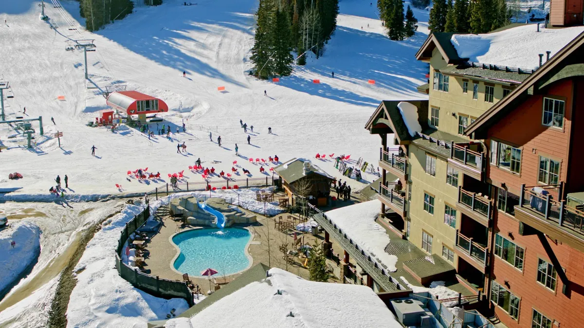 This vibrant exterior shot captures the ski slopes, a swimming pool, hotel balconies, and both skiers and snowboarders in action. The scene exudes energy and adventure, highlighting the property's immediate access to Purgatory Resort's ski and snowboard runs, as well as outdoor relaxation and social spaces.